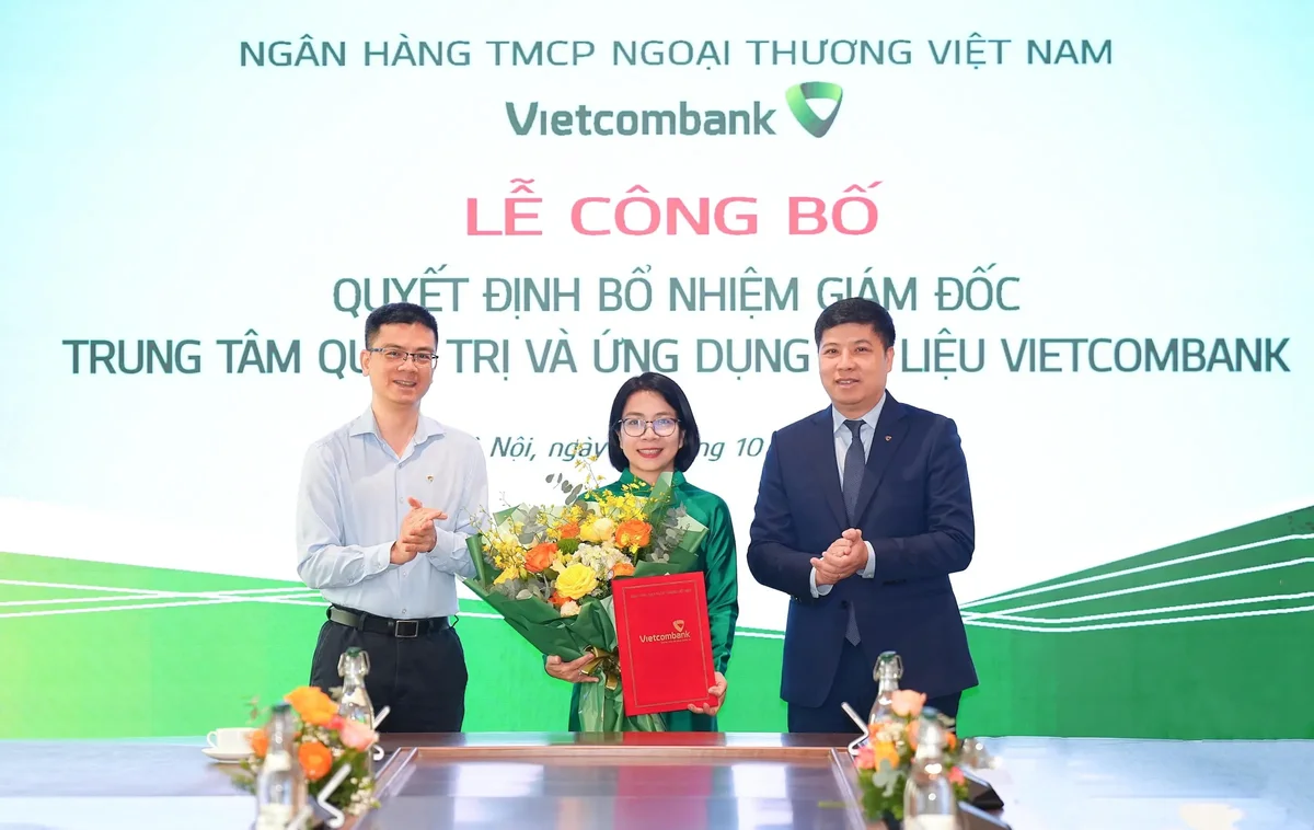 Ông Hồng Quang - Thành viên HĐQT kiêm Giám đốc Khối Nhân sự (bên phải) và ông Trần Thanh Nam - Giám đốc Khối Dữ liệu kiêm Giám đốc Trí tuệ nhân tạo (bên trái) trao quyết định và tặng hoa chúc mừng bà Nguyễn Thị Diệu Thuý - tân Giám đốc Trung tâm quản trị và ứng dụng dữ liệu Vietcombank