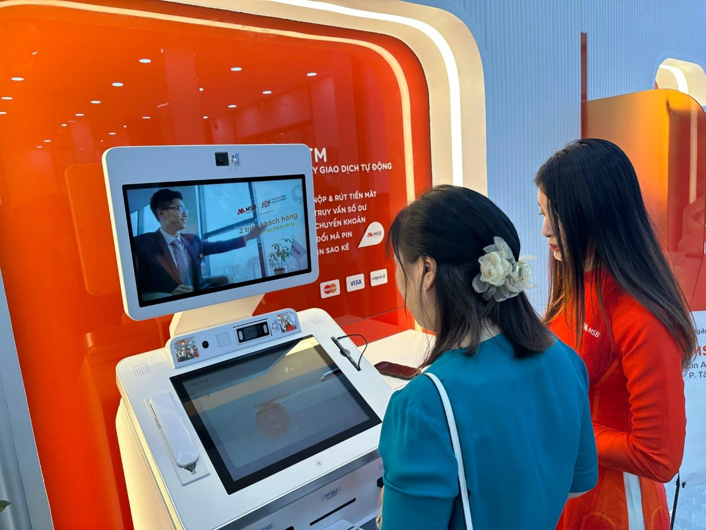 Cán bộ, nhân viên viên MSB đang trực tiếp hướng dẫn và tư vấn cho khách hàng sử dụng máy giao dịch M.Digi Bank
