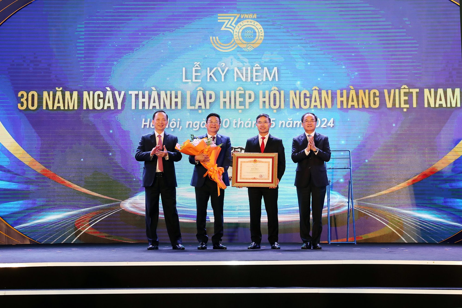 Thứ trưởng Bộ Nội vụ Vũ Chiến Thắng và Phó Thống đốc thường trực Ngân hàng Nhà nước Đào Minh Tú trao Bằng khen của Thủ tướng Chính phủ và hoa chúc mừng cho Hiệp hội Ngân hàng Việt Nam, tháng 5/2024