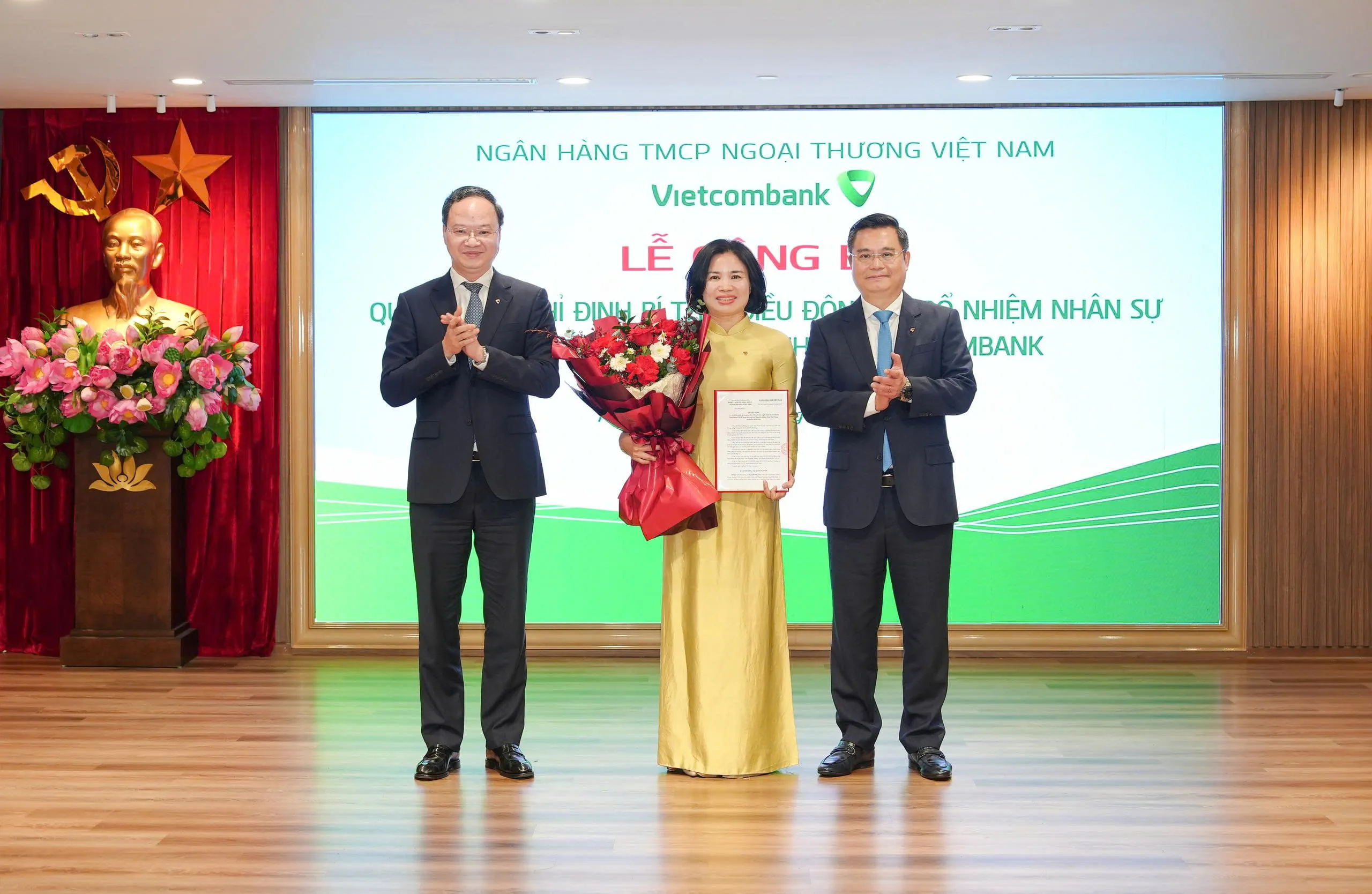 Ông Nguyễn Thanh Tùng - Ủy viên BCH Đảng bộ Chính phủ, Bí thư Đảng ủy, Chủ tịch HĐQT (bên phải) trao quyết định và ông Lê Quang Vinh - Phó Bí thư Đảng ủy, Thành viên HĐQT, Tổng Giám đốc (bên trái) tặng hoa chúc mừng bà Nguyễn Thị Vân - tân Bí thư Chi bộ, Giám đốc Vietcombank Nam Hải Phòng