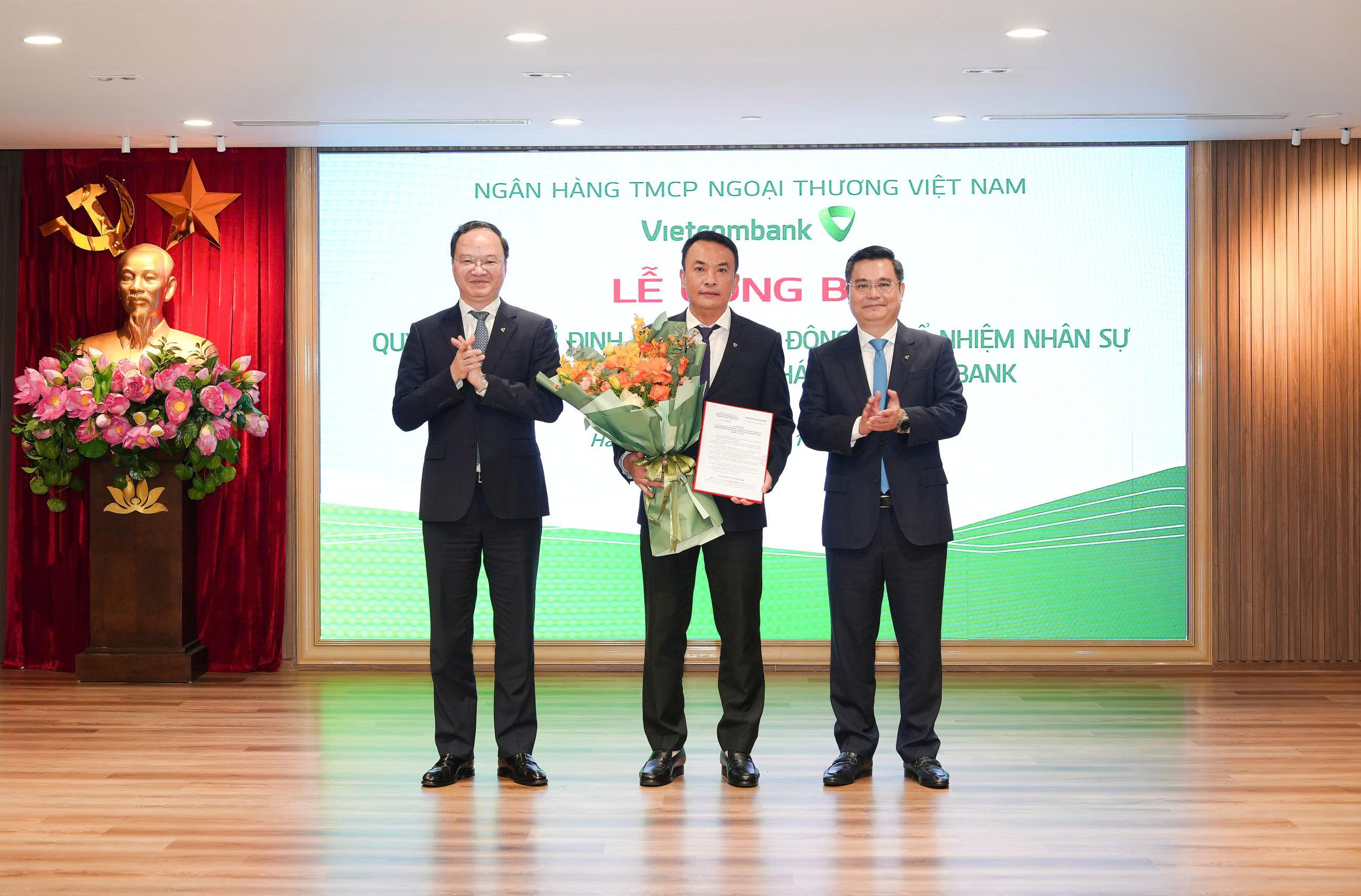 Ông Nguyễn Thanh Tùng - Ủy viên BCH Đảng bộ Chính phủ, Bí thư Đảng ủy, Chủ tịch HĐQT (bên phải) trao quyết định và ông Lê Quang Vinh - Phó Bí thư Đảng ủy, Thành viên HĐQT, Tổng Giám đốc (bên trái) tặng hoa chúc mừng ông Lê Hoàng Cương - tân Bí thư Chi bộ, Giám đốc Vietcombank Đông Hải Phòng