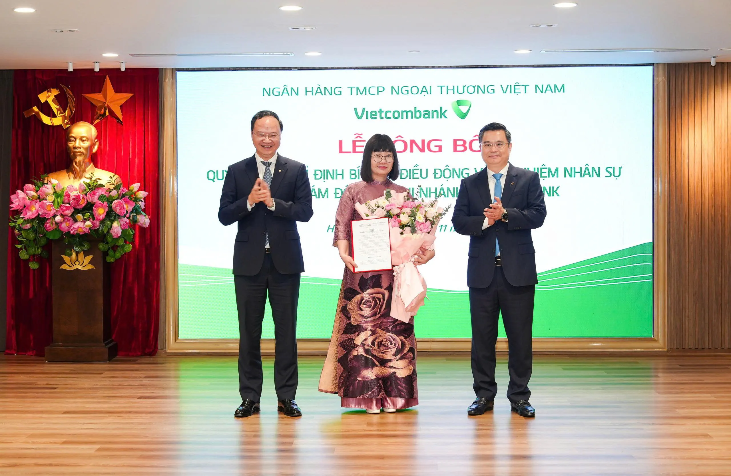 Ông Nguyễn Thanh Tùng - Ủy viên BCH Đảng bộ Chính phủ, Bí thư Đảng ủy, Chủ tịch HĐQT (bên phải) trao quyết định và ông Lê Quang Vinh - Phó Bí thư Đảng ủy, Thành viên HĐQT, Tổng Giám đốc (bên trái) tặng hoa chúc mừng bà Trần Thị Nga - tân Phó Bí thư phụ trách Chi bộ, Phó Giám đốc phụ trách điều hành Vietcombank Lạng Sơn