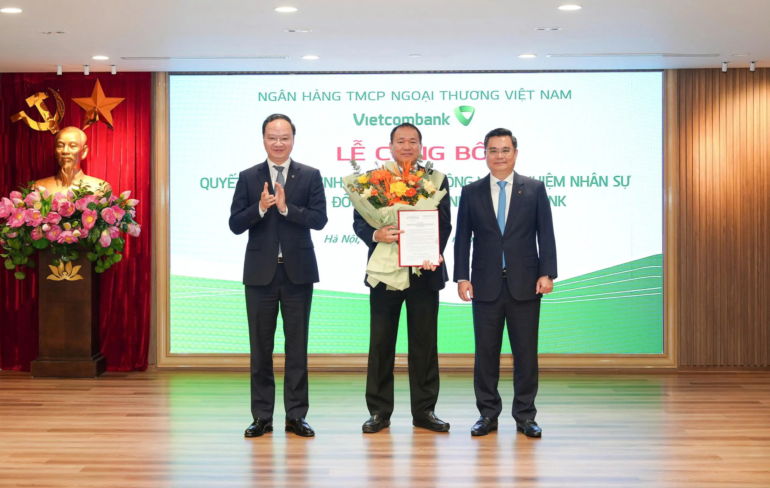 Ông Nguyễn Thanh Tùng - Ủy viên BCH Đảng bộ Chính phủ, Bí thư Đảng ủy, Chủ tịch HĐQT (bên phải) trao quyết định và ông Lê Quang Vinh - Phó Bí thư Đảng ủy, Thành viên HĐQT, Tổng Giám đốc (bên trái) tặng hoa chúc mừng ông Lê Xuân Trường - tân Bí thư Chi bộ, Giám đốc Vietcombank Tân Bắc Ninh