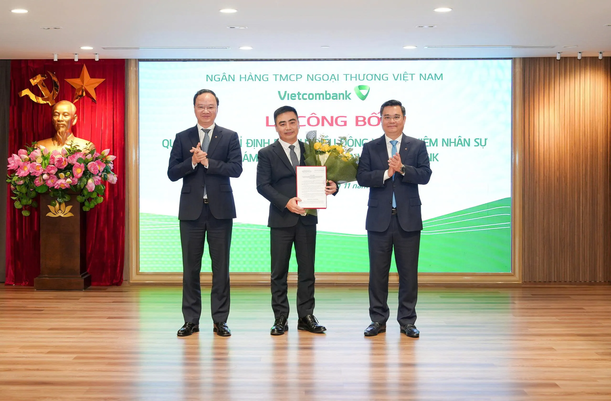 Ông Nguyễn Thanh Tùng - Ủy viên BCH Đảng bộ Chính phủ, Bí thư Đảng ủy, Chủ tịch HĐQT (bên phải) trao quyết định và ông Lê Quang Vinh - Phó Bí thư Đảng ủy, Thành viên HĐQT, Tổng Giám đốc (bên trái) tặng hoa chúc mừng ông Nguyễn Quang Lý - tân Bí thư Chi bộ, Giám đốc Vietcombank Thành Công