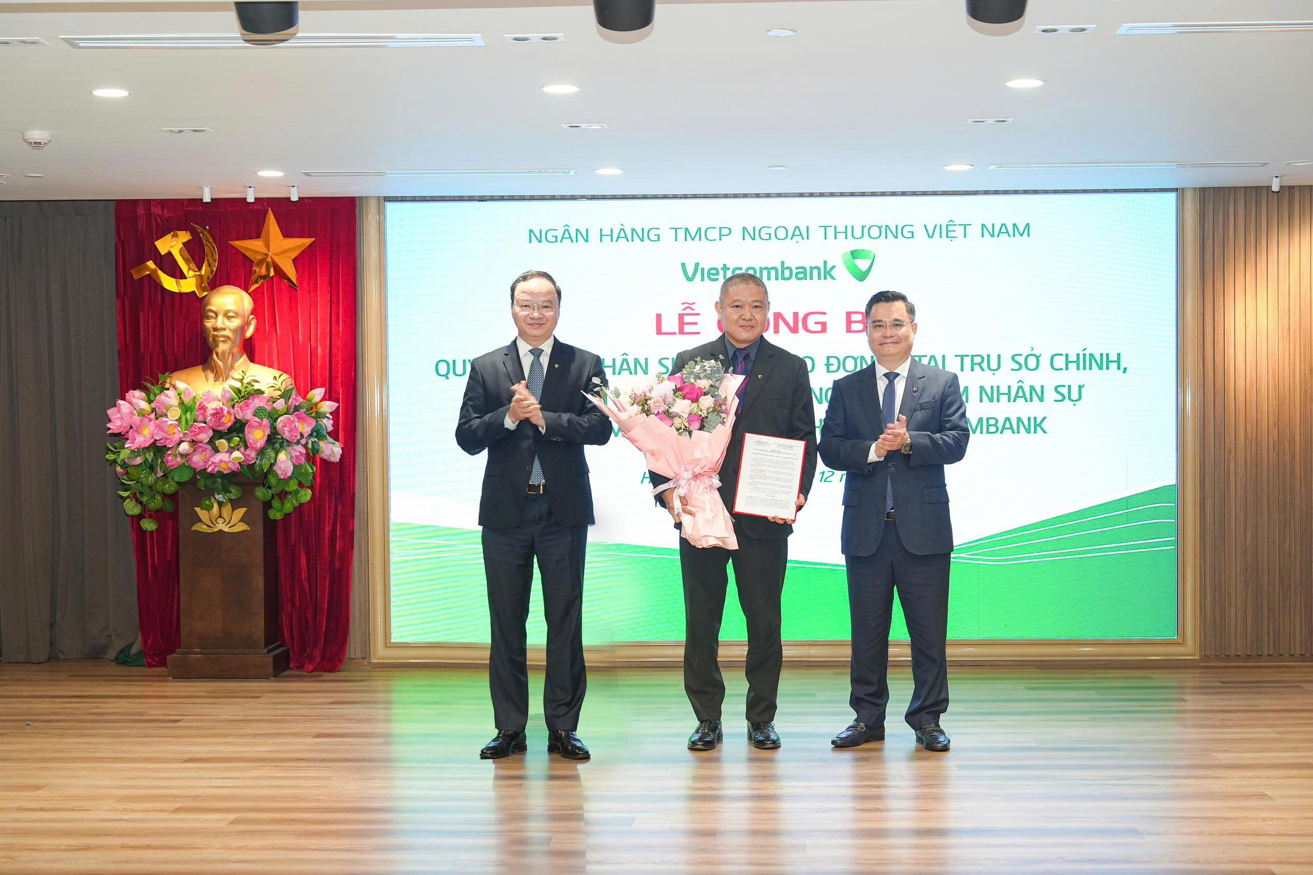 Ông Nguyễn Thanh Tùng - Ủy viên BCH Đảng bộ Chính phủ, Bí thư Đảng ủy, Chủ tịch HĐQT (bên phải) trao quyết định và ông Lê Quang Vinh - Phó Bí thư Đảng ủy, Thành viên HĐQT, Tổng Giám đốc (bên trái) tặng hoa chúc mừng ông Trần Thuỳ Dương - Phó Bí thư Đảng ủy phụ trách, Phó Giám đốc phụ trách điều hành Vietcombank Nam Định