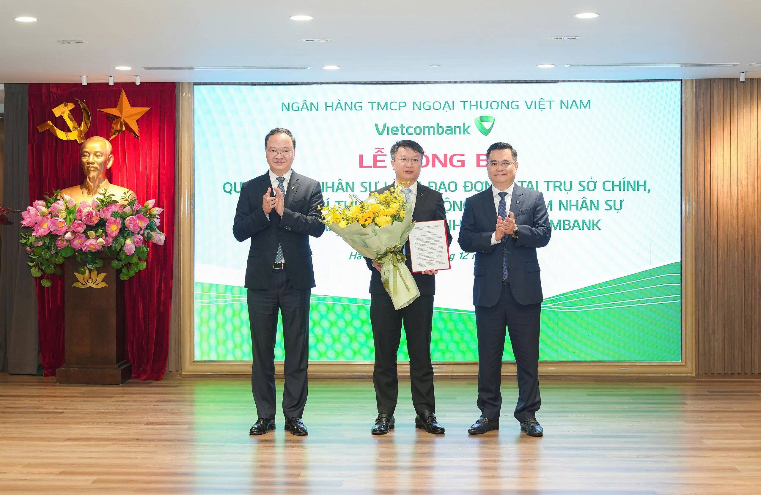 Ông Nguyễn Thanh Tùng - Ủy viên BCH Đảng bộ Chính phủ, Bí thư Đảng ủy, Chủ tịch HĐQT (bên phải) trao quyết định và ông Lê Quang Vinh - Phó Bí thư Đảng ủy, Thành viên HĐQT, Tổng Giám đốc (bên trái) tặng hoa chúc mừng ông Đinh Mạnh Tuân - tân Bí thư Chi bộ, Giám đốc Vietcombank Đông Đô