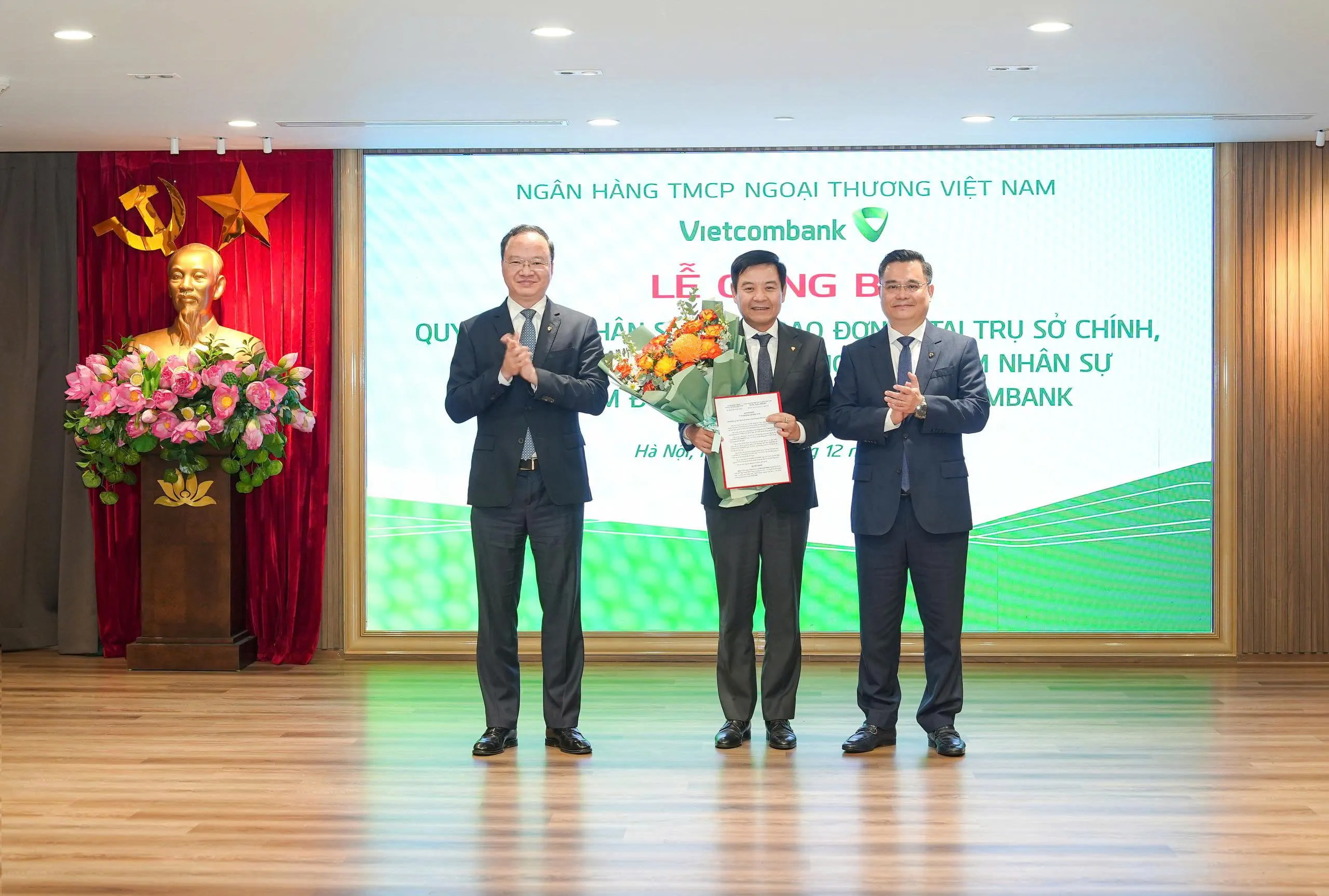 Ông Nguyễn Thanh Tùng - Ủy viên BCH Đảng bộ Chính phủ, Bí thư Đảng ủy, Chủ tịch HĐQT (bên phải) trao quyết định và ông Lê Quang Vinh - Phó Bí thư Đảng ủy, Thành viên HĐQT, Tổng Giám đốc (bên trái) tặng hoa chúc mừng ông Trần Mạnh Hùng - tân Bí thư Đảng ủy, Giám đốc Vietcombank Chương Dương