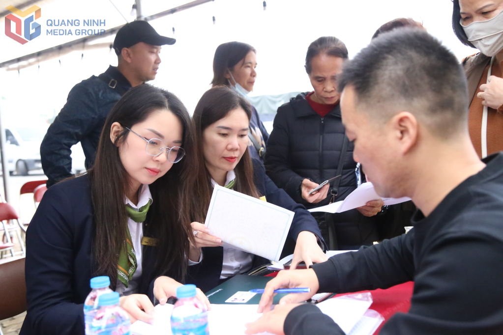 Nhân viên Ngân hàng Vietcombank Quảng Ninh hướng dẫn các hộ kinh doanh người Trung Quốc tại Chợ Móng Cái cài đặt QR thanh toán quốc tế.