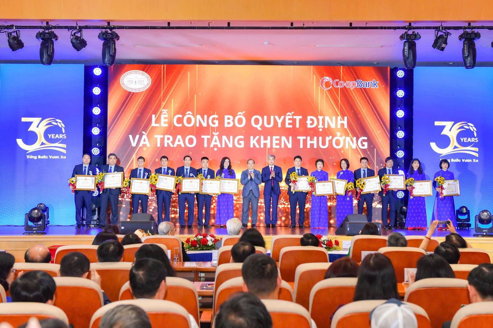Đồng chí Đoàn Thái Sơn - Phó Thống đốc NHNN Việt Nam, đồng chí Nguyễn Quốc Cường - Chủ tịch HĐQT Co-opBank trao tặng bằng khen và hoa chúc mừng 14 tập thể là các đơn vị tại Trụ sở chính và Chi nhánh Co-opBank vinh dự được nhận Bằng khen của Thống đốc NHNN vì đã có thành tích xuất sắc góp phần hoàn thành nhiệm vụ Ngân hàng tại buổi lễ kỷ niệm 30 năm thành lập Co-opBank