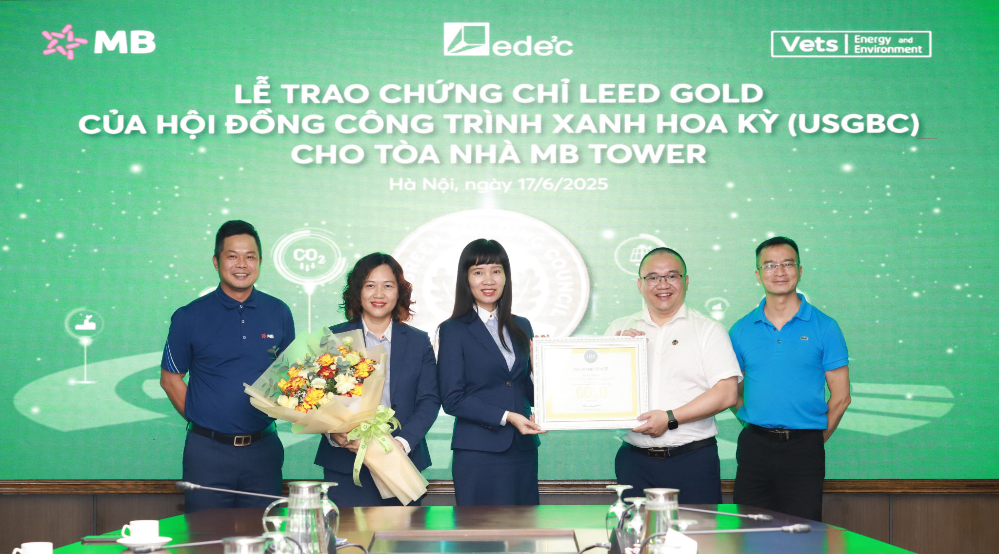Đại diện MB, bà Trần Thị Bảo Quế - Thành viên Ban Điều hành cùng lãnh đạo khối Hành chính nhận chứng nhận và hoa chúc mừng từ ông Dương Chí Công – Giám đốc Kỹ thuật Công ty Vets và ông Trần Thành Vũ – Giám đốc EDeec