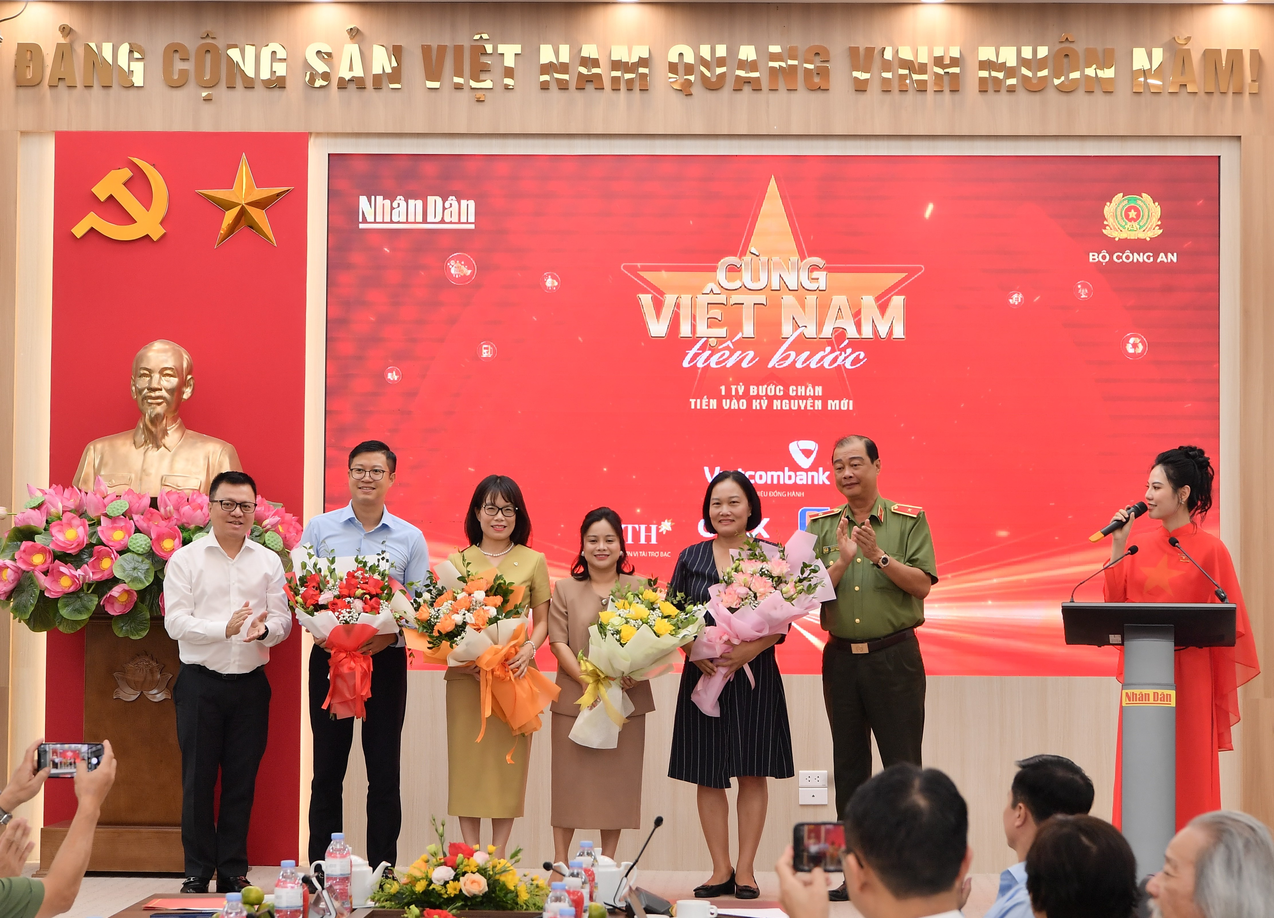 Đ/c Lê Quốc Minh - Ủy viên BCH Trung ương Đảng, Tổng Biên tập Báo Nhân Dân, Phó Trưởng Ban Tuyên giáo và Dân vận Trung ương, Chủ tịch Hội Nhà báo Việt Nam (bên trái) và Thiếu tướng Lê Hồng Hiệp - Phó Cục trưởng Cục Công tác chính trị Bộ Công an (bên phải) tặng hoa cho đại diện thương hiệu đồng hành Vietcombank - bà Đoàn Hồng Nhung, Thành viên Ban Điều hành, Giám đốc Khối Bán lẻ (thứ 3 từ trái sang) cùng các nhà tài trợ khác