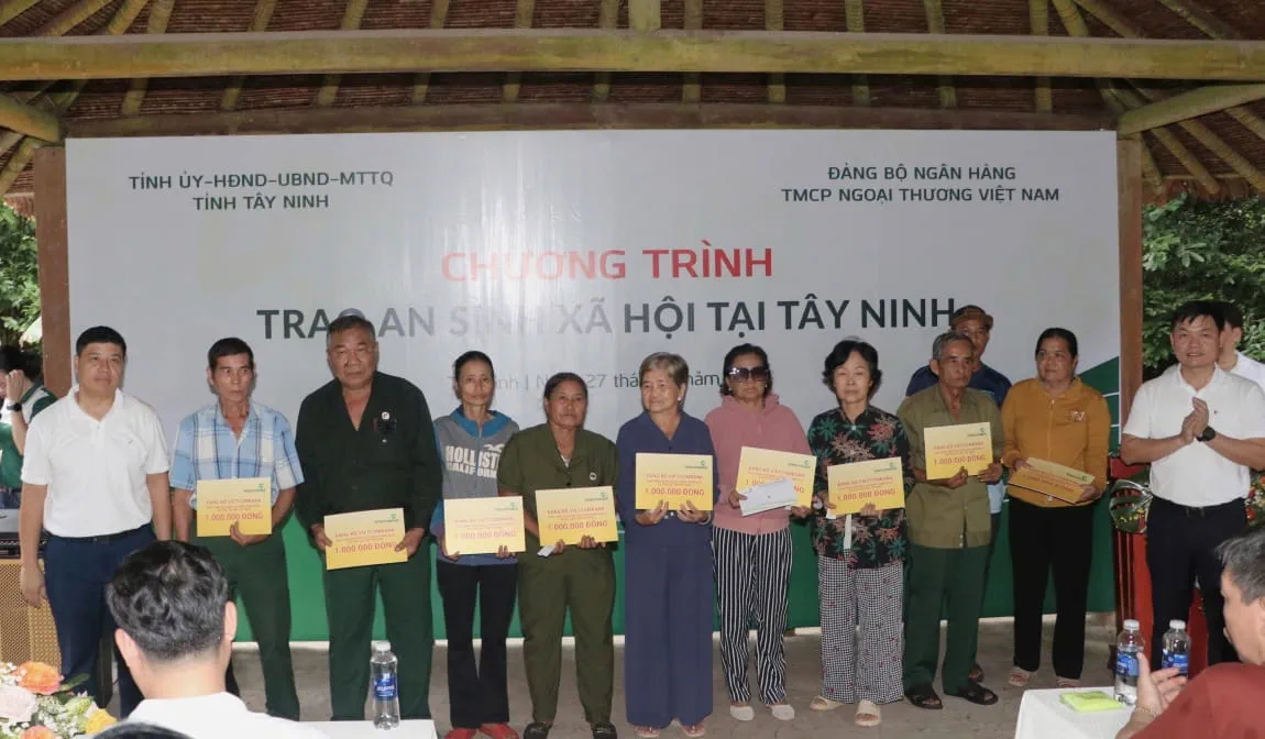 Đ/c Hồng Quang - Thành viên HĐQT, Chủ tịch Công đoàn Vietcombank (ngoài cùng bên trái) và đ/c Nguyễn Danh Phương - Phó Bí thư Đảng ủy Vietcombank (ngoài cùng,bên phải) trao biển biểu trưng các suất quà hỗ trợ cho các hộ nghèo, gia đình chính sách tại tỉnh Tây Ninh