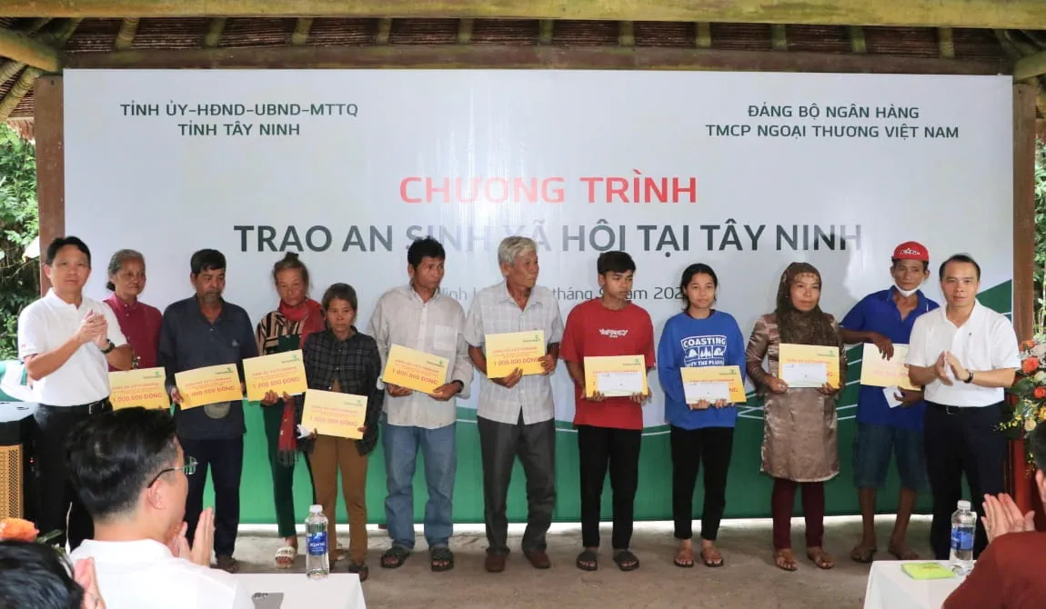 Đ/c Nguyễn Mạnh Hùng - Uỷ viên BTV Đảng uỷ, Thành viên HĐQT Vietcombank (ngoài cùng bên trái) và đ/c Đỗ Việt Hùng - Uỷ viên BTV Đảng uỷ, Thành viên HĐQT Vietcombank (ngoài cùng bên phải) trao biển biểu trưng các suất quà hỗ trợ cho các hộ nghèo, gia đình chính sách tại tỉnh Tây Ninh