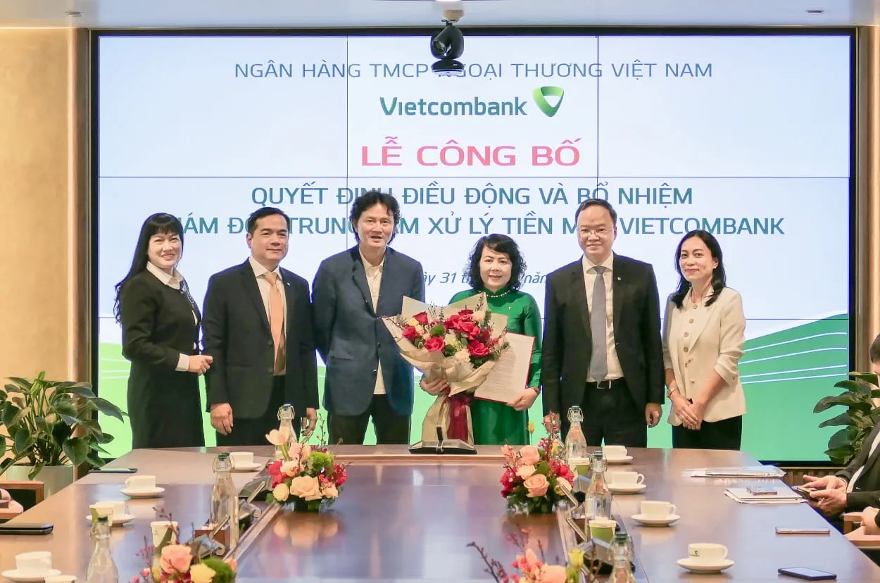 Ông Lê Quang Vinh - Phó Bí thư Đảng ủy, Thành viên HĐQT, Tổng Giám đốc Vietcombank (thứ 2, từ phải sang) và ông Nguyễn Văn Tuân - Phó Tổng Giám đốc Vietcombank (thứ 3, từ trái sang) trao quyết định bổ nhiệm và tặng hoa chúc mừng bà Quách Kim Cúc - tân Giám đốc Trung tâm Xử lý tiền mặt
