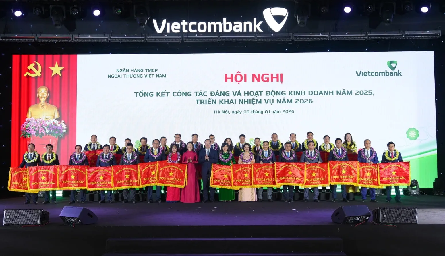 Đ/c Lê Quang Vinh - Phó Bí thư Đảng ủy, Thành viên HĐQT, Tổng Giám đốc Vietcombank (thứ 9 từ trái sang, hàng đầu) và đ/c Nguyễn Thị Kim Oanh - Ủy viên BTV Đảng ủy, Thành viên HĐQT Vietcombank (thứ 8 từ trái sang, hàng đầu) trao cờ và tặng hoa chúc mừng 31 chi nhánh “hoàn thành xuất sắc nhiệm vụ” năm 2025