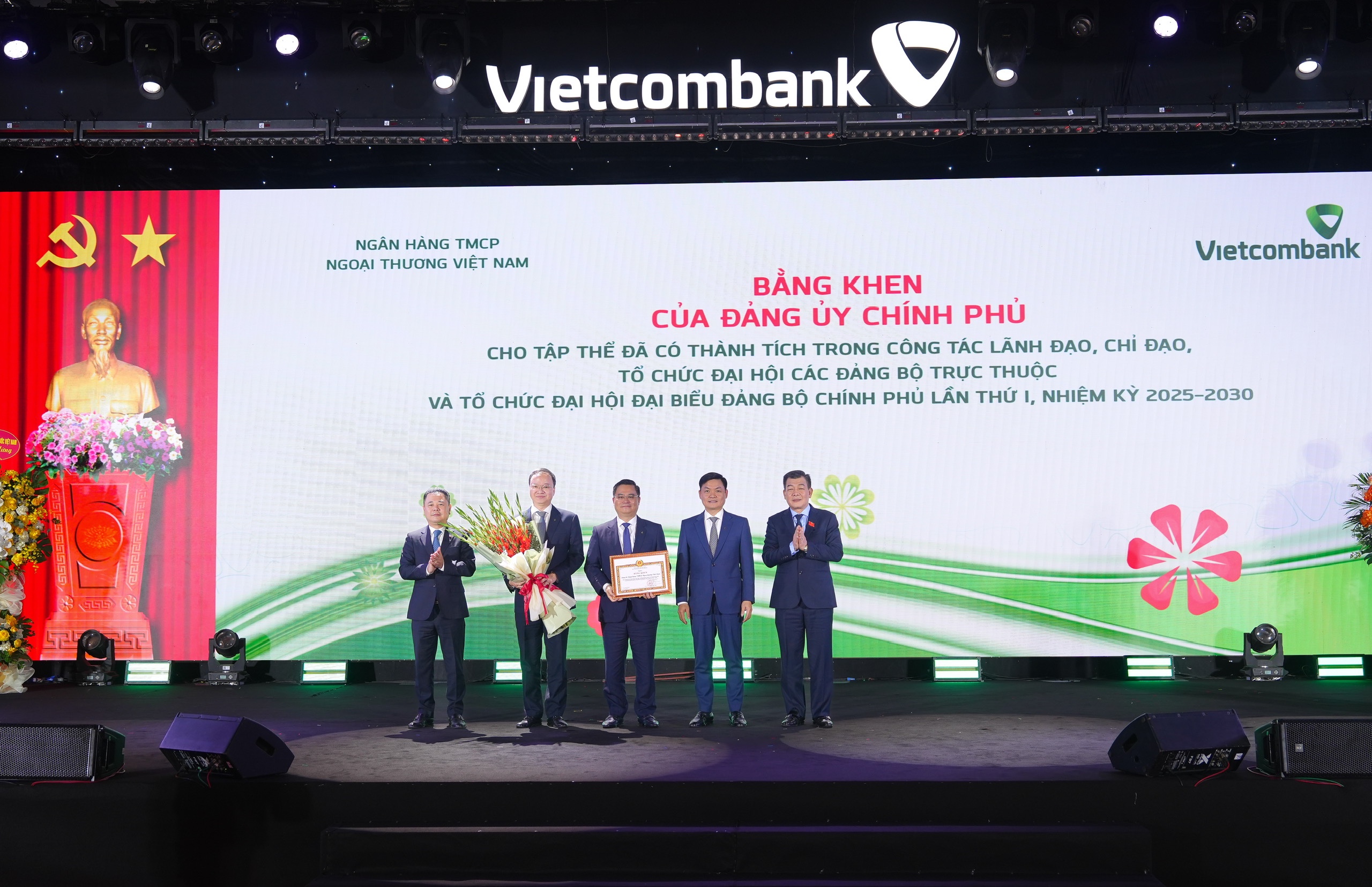 Đại diện Vietcombank, đ/c Nguyễn Thanh Tùng - Ủy viên Ban Chấp hành Đảng bộ Chính phủ, Bí thư Đảng ủy, Chủ tịch HĐQT (đứng giữa); đ/c Lê Quang Vinh - Phó Bí thư Đảng ủy, Thành viên HĐQT, Tổng Giám đốc (thứ 2 từ trái sang); đ/c Nguyễn Danh Phương - Phó Bí thư thường trực Đảng ủy (thứ 2 từ phải sang) nhận bằng khen của Đảng ủy Chính phủ với thành tích trong công tác lãnh đạo đã tổ chức đại hội các Đảng bộ trực thuộc và tổ chức Đại hội đại biểu Đảng bộ Chính phủ lần thứ nhất nhiệm kỳ 2025-2030. Đ/c Nguyễn Đức Phong - Phó Bí thư chuyên trách Đảng ủy Chính phủ (ngoài cùng bên phải) trao tặng bằng khen và đ/c Nguyễn Ngọc Cảnh - Ủy viên BTV Đảng ủy, Phó Thống đốc NHNN (ngoài cùng bên trái) tặng hoa chúc mừng