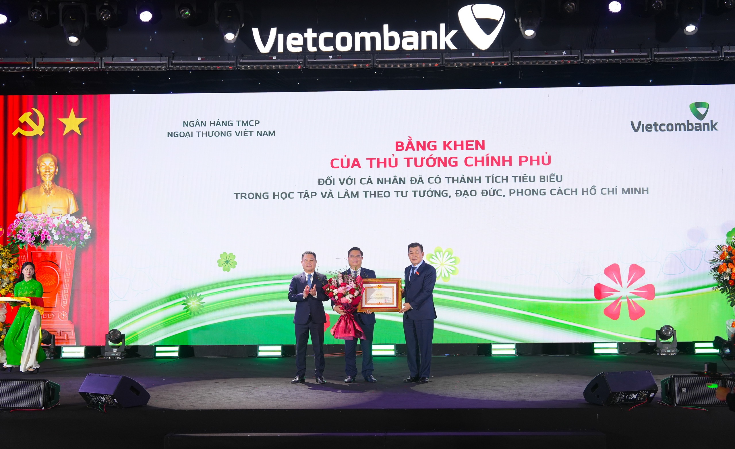 Đ/c Nguyễn Đức Phong - Phó Bí thư chuyên trách Đảng ủy Chính phủ (bên phải) trao tặng bằng khen của Thủ tướng Chính phủ và đ/c Nguyễn Ngọc Cảnh - Ủy viên BTV Đảng ủy, Phó Thống đốc NHNN (bên trái) tặng hoa chúc mừng đ/c Nguyễn Thanh Tùng - Ủy viên BCH Đảng bộ Chính phủ, Bí thư Đảng ủy, Chủ tịch HĐQT Vietcombank vì đã có thành tích tiêu biểu trong học tập và làm theo tấm gương đạo đức, phong cách Hồ Chí Minh