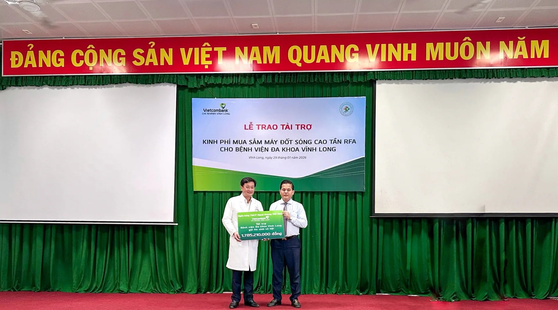 Ông Vũ Trung Kiên (bên phải) - Giám đốc Vietcombank Vĩnh Long trao bảng tượng trưng kinh phí tài trợ cho ông Nguyễn Thanh Truyền - Giám đốc Bệnh viện Đa khoa Vĩnh Long