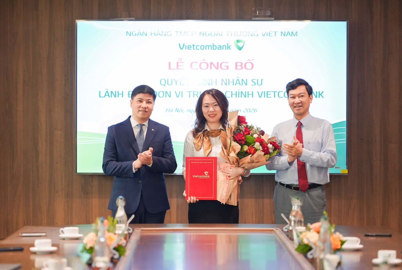 Ông Hồng Quang - Thành viên HĐQT kiêm Giám đốc Khối Nhân sự Vietcombank (bên trái) trao quyết định và ông Vũ Quang Đông - Phó Giám đốc phụ trách Khối Vốn & Thị trường (bên phải) tặng hoa chúc mừng bà Phan Hồng Nhung - tân Phó Trưởng ban Định chế tài chính TSC Vietcombank