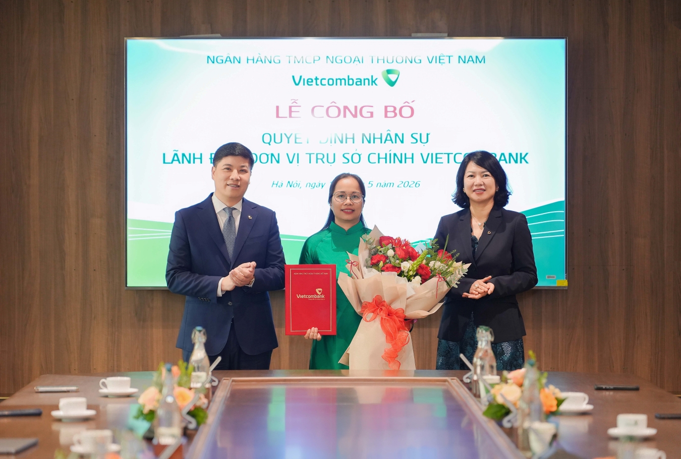 Ông Hồng Quang - Thành viên HĐQT kiêm Giám đốc Khối Nhân sự Vietcombank (bên trái) trao quyết định và bà Nguyễn Thị Hồng Vân - Giám đốc Khối Pháp chế & Tuân thủ (bên phải) tặng hoa chúc mừng bà Hoàng Hương Trang - tân Phó trưởng phòng Quản lý rủi ro tích hợp TSC Vietcombank