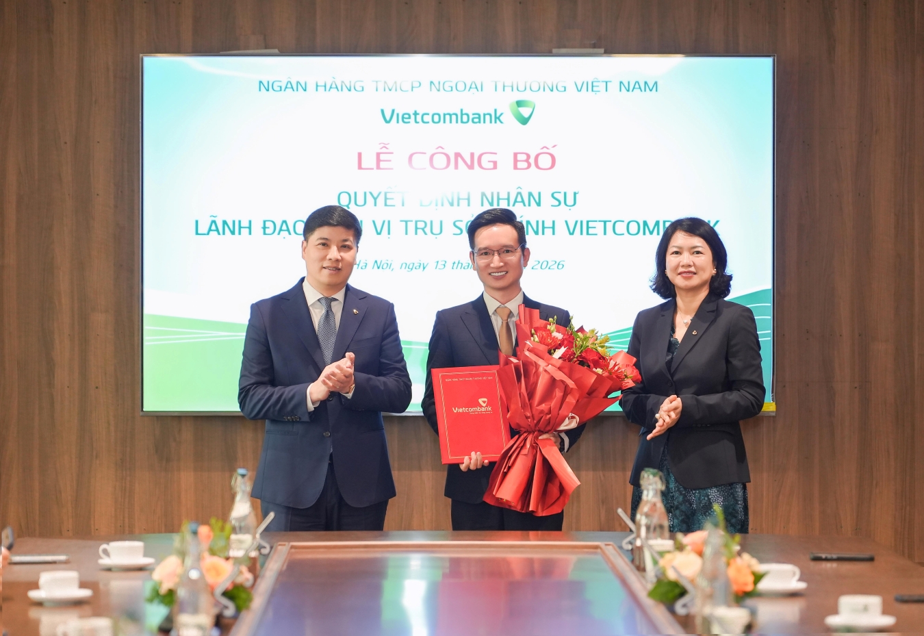 Ông Hồng Quang - Thành viên HĐQT kiêm Giám đốc Khối Nhân sự Vietcombank (bên trái) trao quyết định và bà Nguyễn Thị Hồng Vân - Giám đốc Khối Pháp chế & Tuân thủ (bên phải) tặng hoa chúc mừng ông Nguyễn Hoàng Thao - tân Phó trưởng phòng phụ trách phòng Mô hình và công cụ quản trị rủi ro TSC Vietcombank