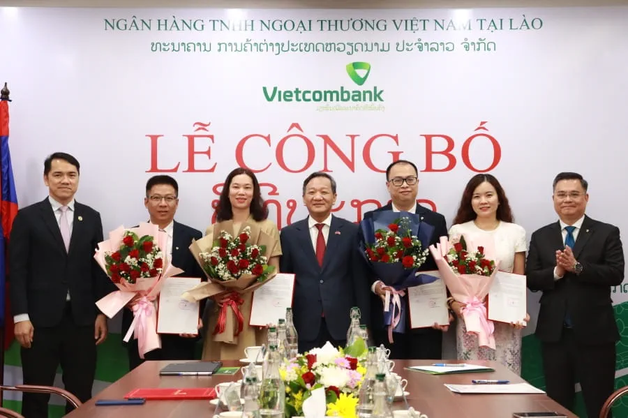 Đ/c Soulysak Thamnuvong - Phó Thống đốc BOL (ngoài cùng bên trái) và đ/c Nguyễn Thanh Tùng - Bí thư Đảng ủy, Chủ tịch HĐQT Vietcombank (ngoài cùng bên phải) trao quyết định và tặng hoa cho các đ/c giữ chức vụ Thành viên HĐQT Vietcombank Lào