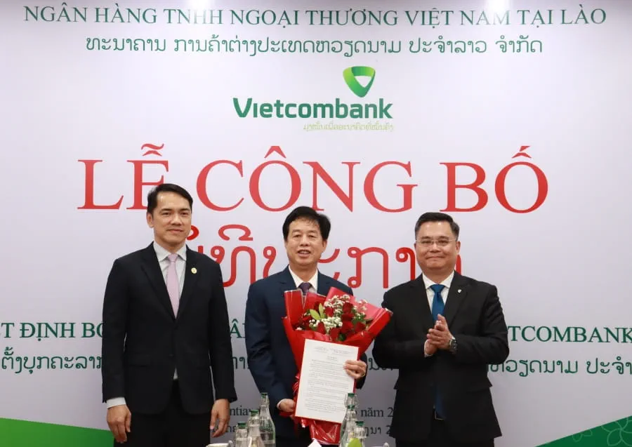 Đ/c Soulysak Thamnuvong - Phó Thống đốc BOL (bên trái) và đ/c Nguyễn Thanh Tùng - Bí thư Đảng ủy, Chủ tịch HĐQT Vietcombank (bên phải) trao quyết định và tặng hoa cho đ/c Nguyễn Mỹ Hào - nguyên Thành viên HĐQT Vietcombank giữ chức vụ Phó Chủ tịch HĐQT kiêm Thành viên HĐQT độc lập Vietcombank Lào
