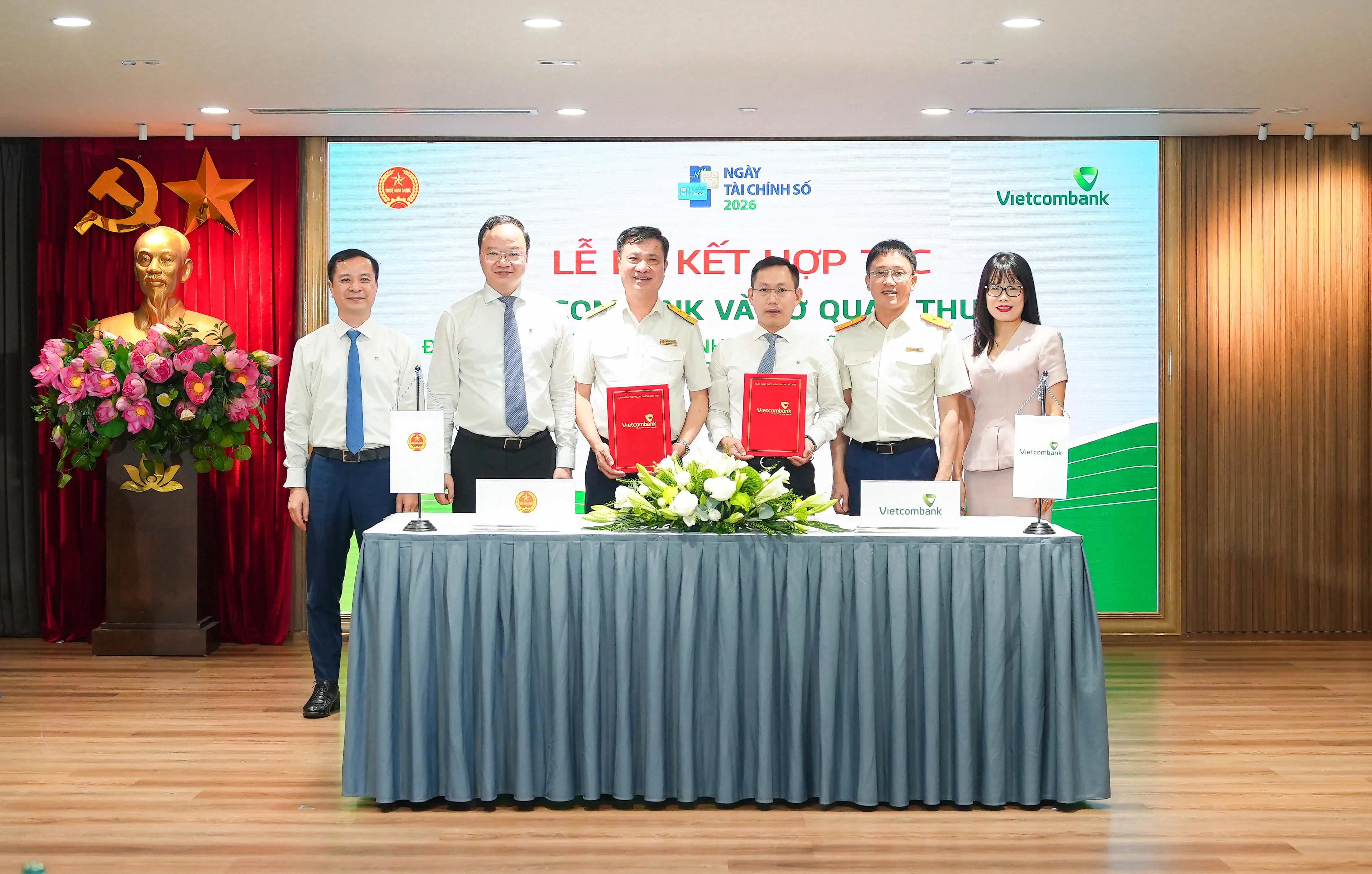 Ông Đặng Kiên Định - Giám đốc Vietcombank Sở Giao dịch (thứ 3, từ phải sang) đại diện cho toàn bộ 18 chi nhánh Vietcombank tại Hà Nội thực hiện ký kết cùng ông Nguyễn Tiến Minh - Phó Cục trưởng Cục Thuế TP. Hà Nội (thứ 3, từ trái sang) dưới sự chứng kiến của đại diện lãnh đạo hai đơn vị