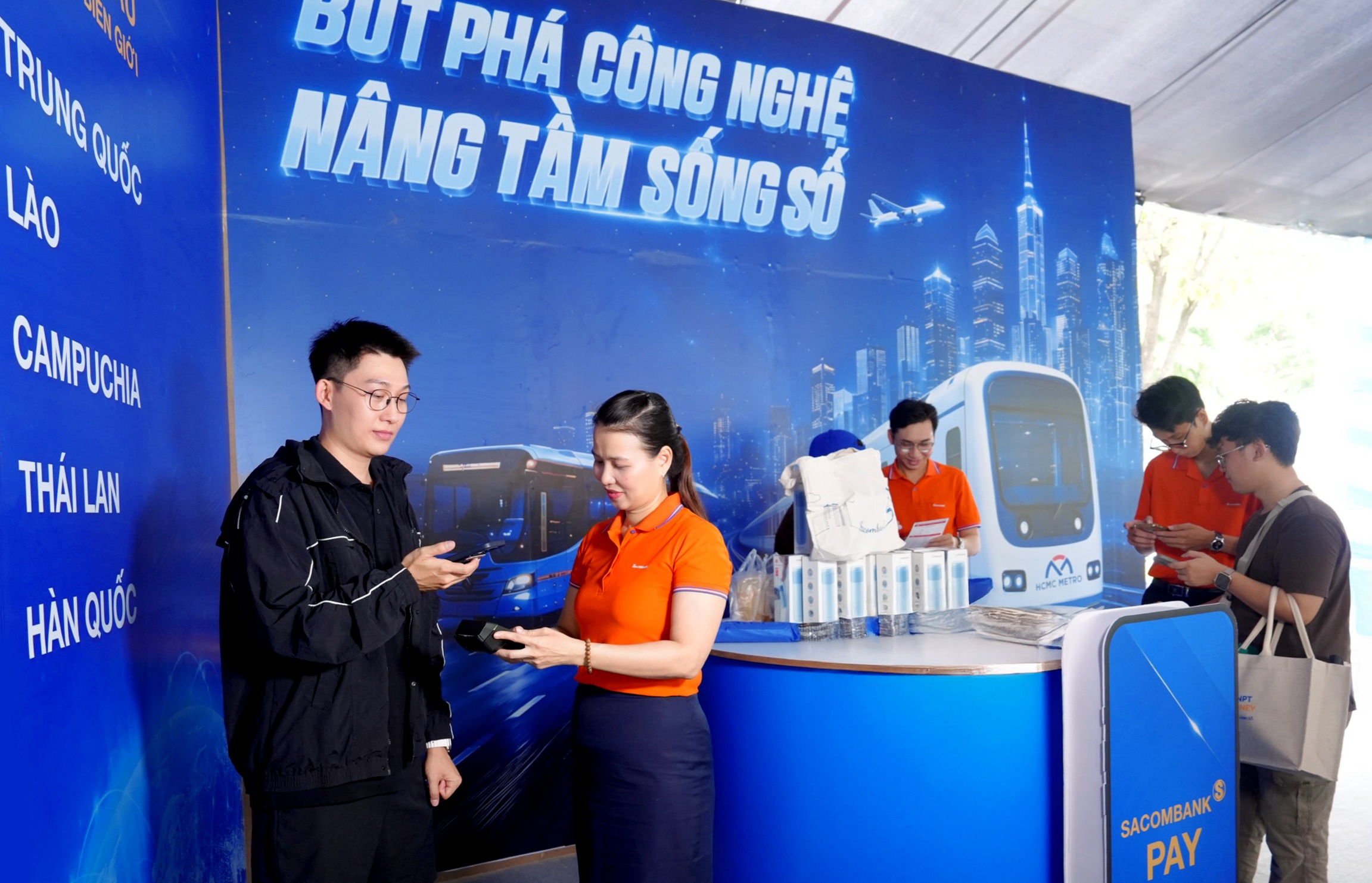 Một du khách Trung Quốc (góc trái) trải nghiệm dịch vụ thanh toán VIETQRGlobal ngay trên app Alipay tại gian hàng SACOMBANK sáng 6/6