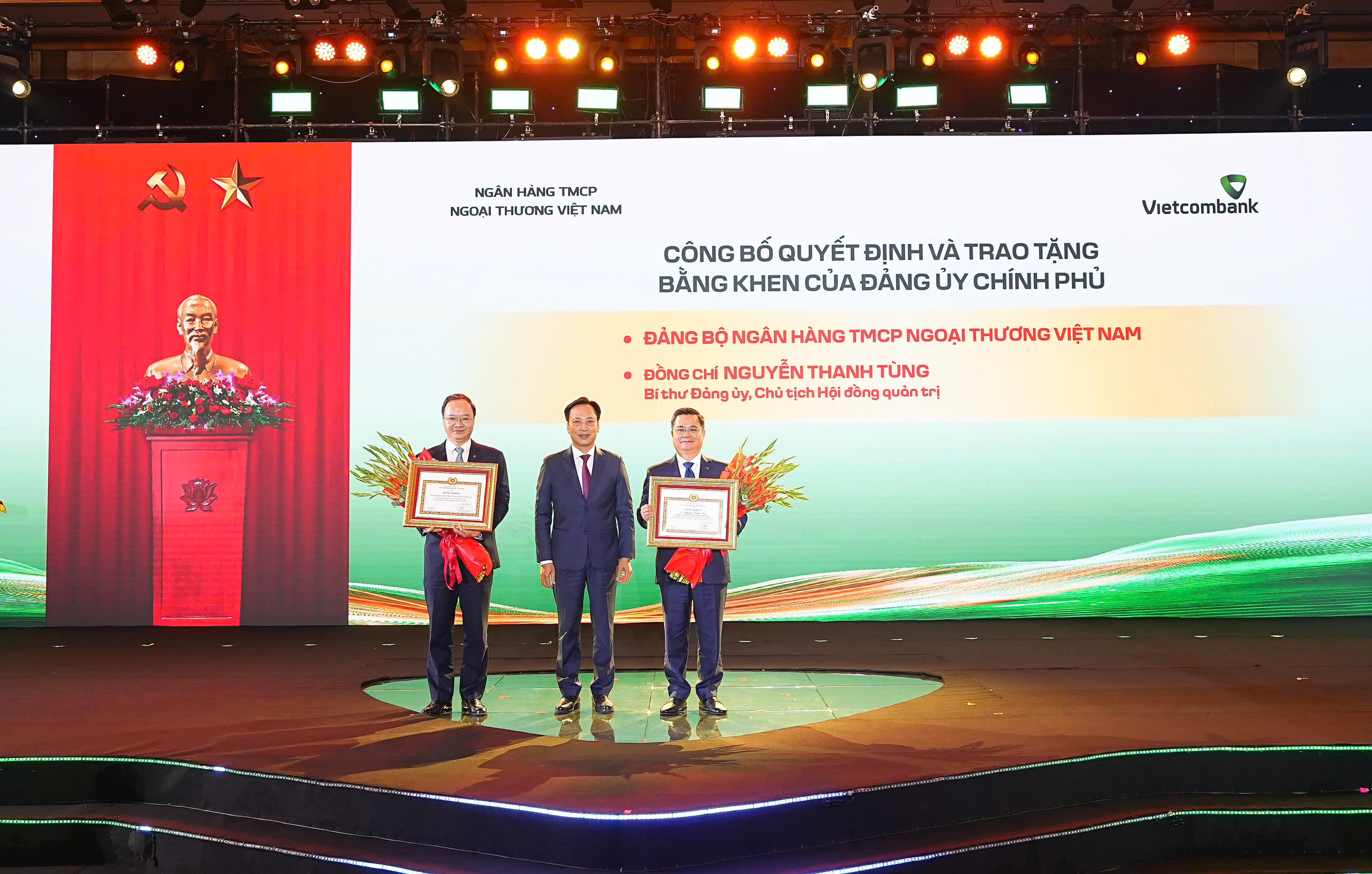 Đại diện Đảng ủy Chính phủ, đ/c Lại Xuân Lâm - Phó Bí thư Chuyên trách trao bằng khen của Đảng ủy Chính phủ tặng Đảng bộ Vietcombank vì đã có thành tích xuất sắc, tiêu biểu hoàn thành vượt mức các chỉ tiêu Nghị quyết Đại hội nhiệm kỳ 2020-2025 và tặng bằng khen cho cá nhân đ/c Nguyễn Thanh Tùng - Bí thư Đảng ủy, Chủ tịch HĐQT Vietcombank (ngoài cùng bên phải) vì những thành tích xuất sắc trong thực hiện Nghị quyết Đại hội nhiệm kỳ 2020-2025. Đ/c Lê Quang Vinh - Phó Bí thư Đảng ủy, Thành viên HĐQT, Tổng Giám đốc (ngoài cùng bên trái) đại diện Đảng bộ Vietcombank nhận bằng khen tập thể